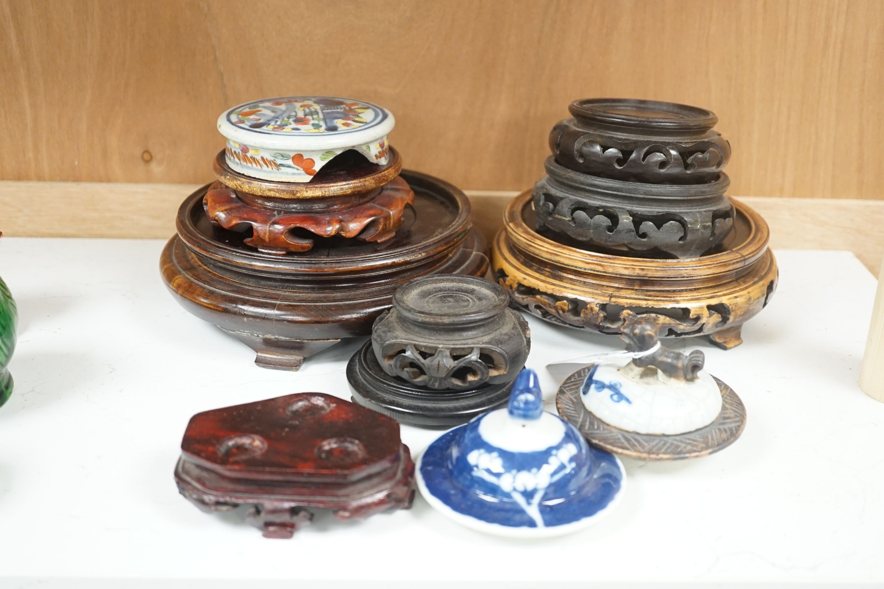 A group of Chinese wooden stands and three ceramics covers.